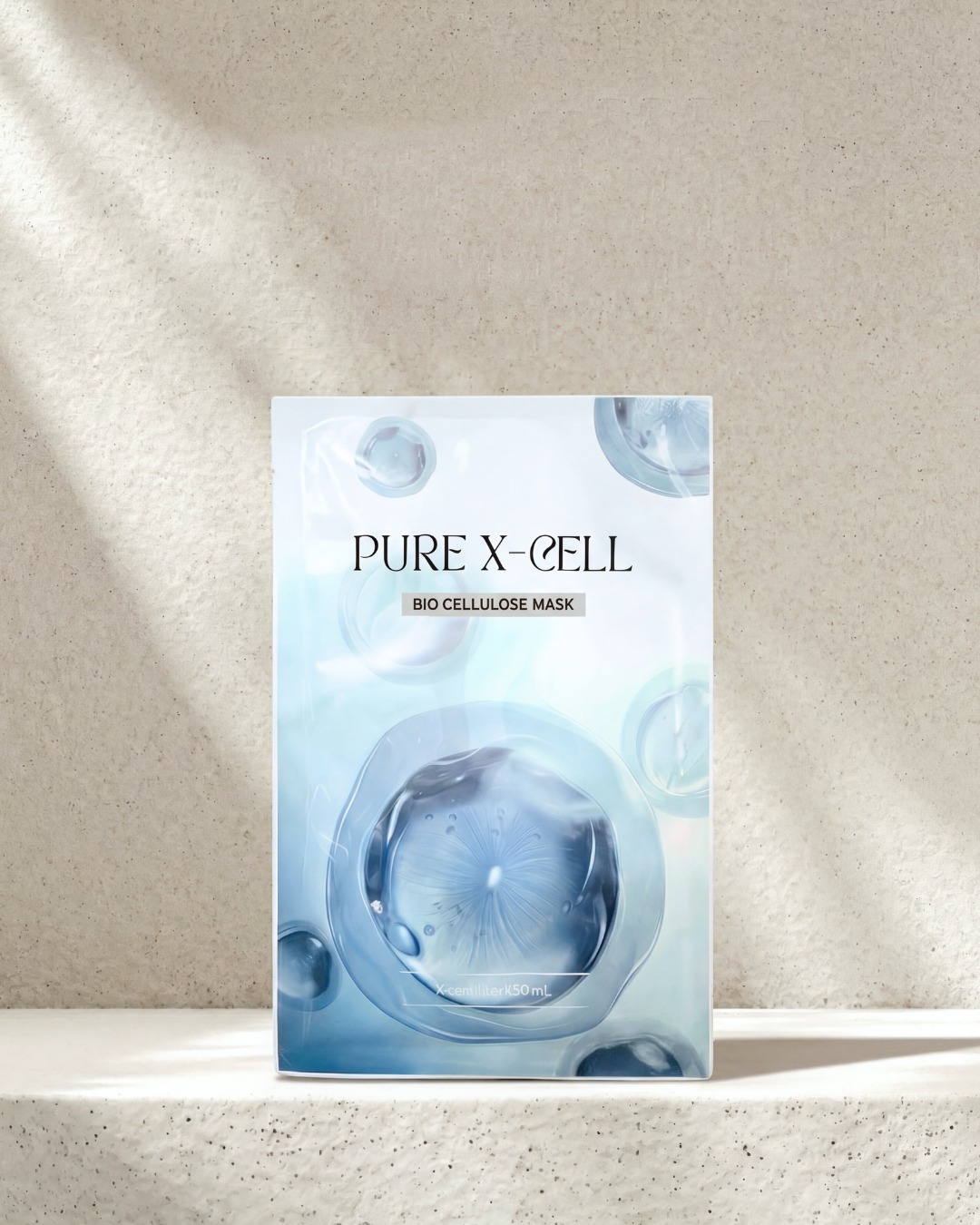PURE X-CELL bio cellulose mask packaging on a textured beige background
